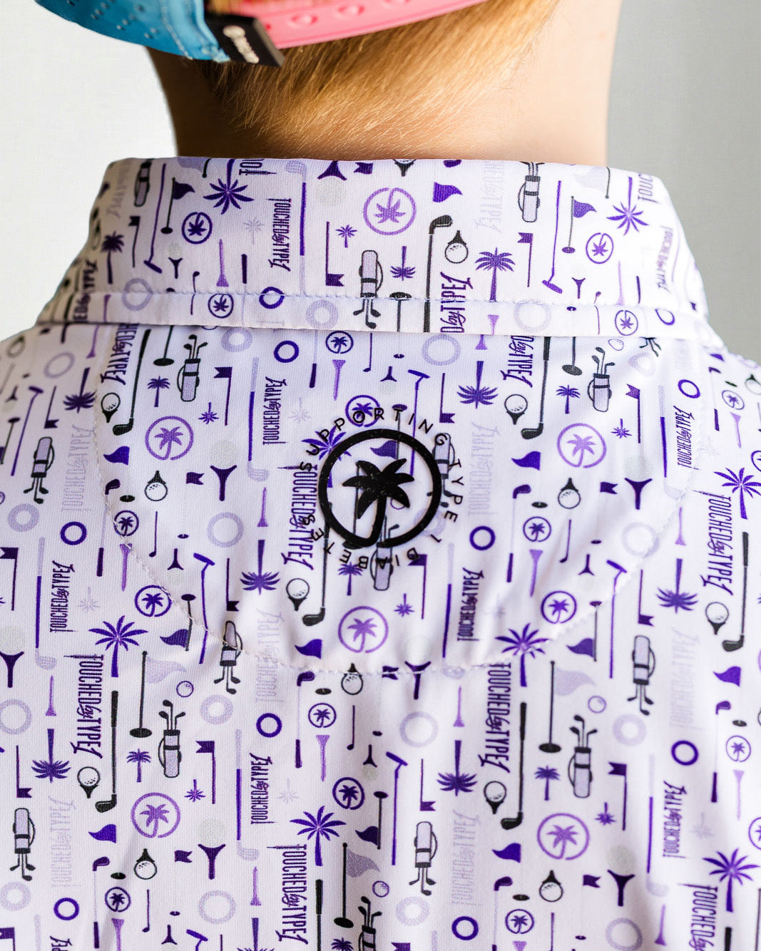 Child wearing a patterned shirt and blue cap against a plain background