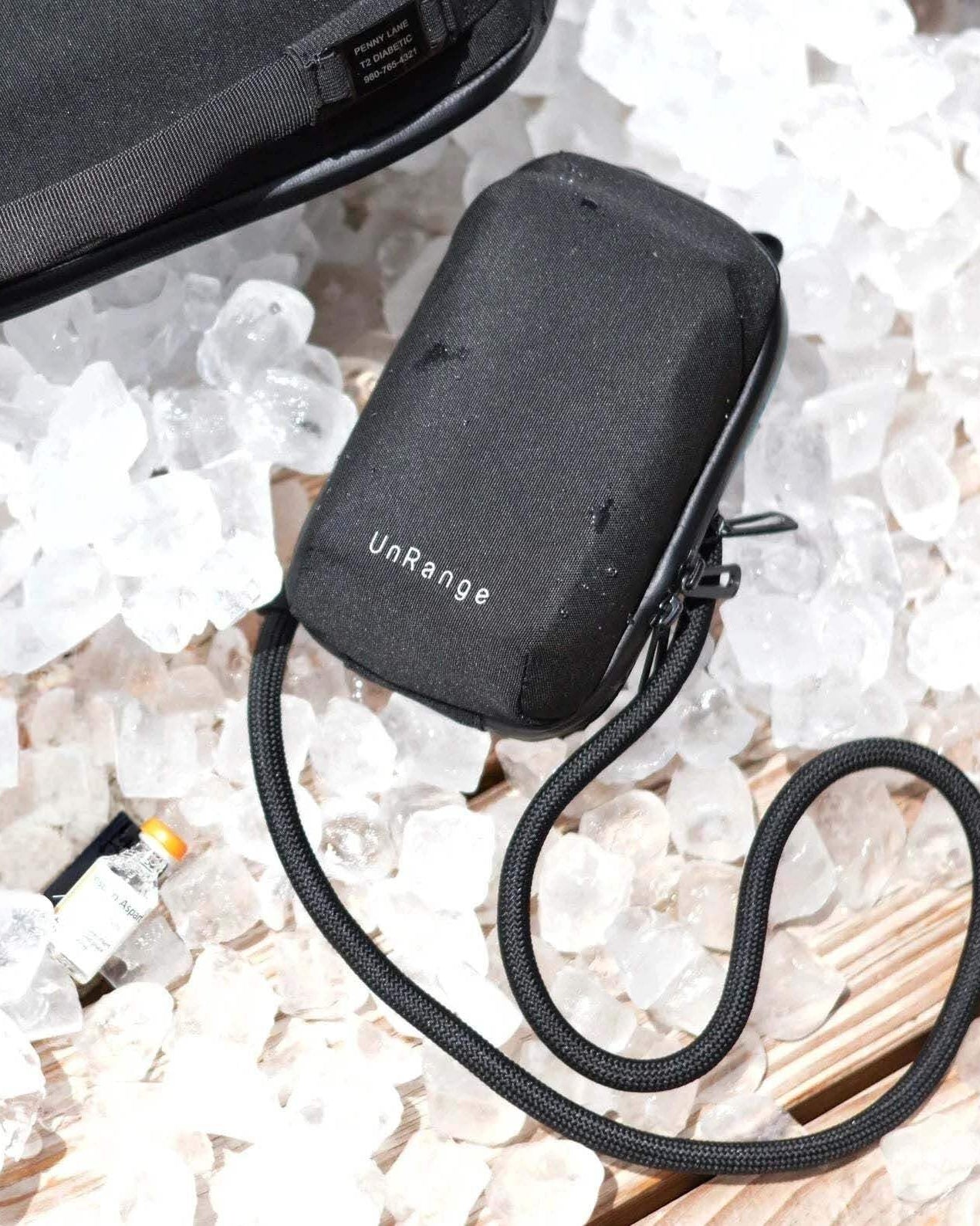 Compact insulated crossbody bag with nylon strap, carabiners, and freezer pack for diabetes medication storage