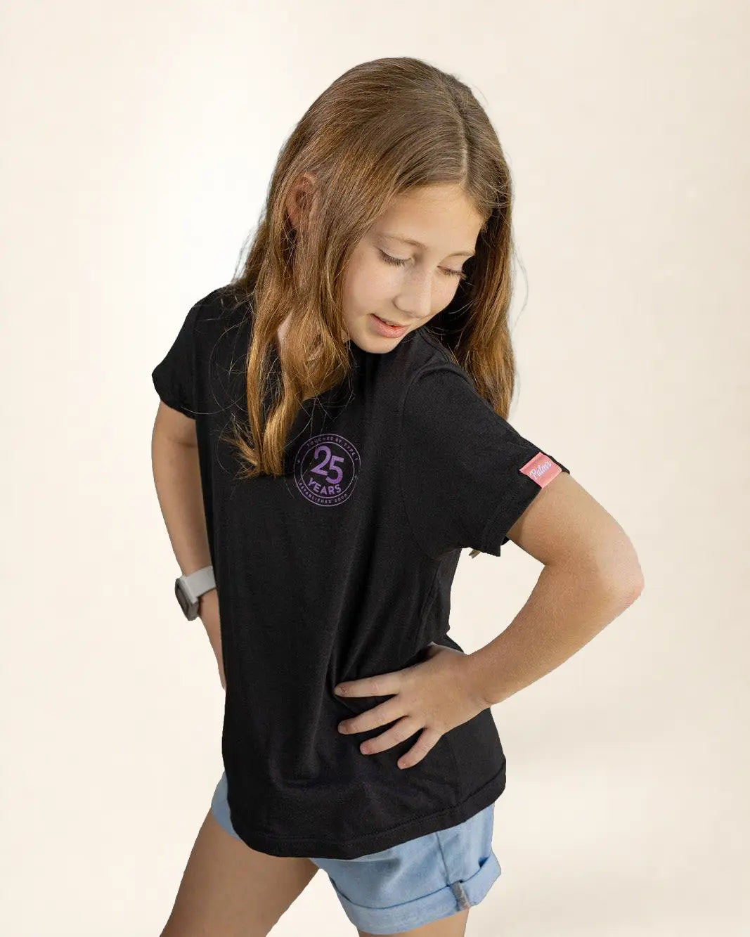 Young girl wearing a black t-shirt with a logo on a beige background