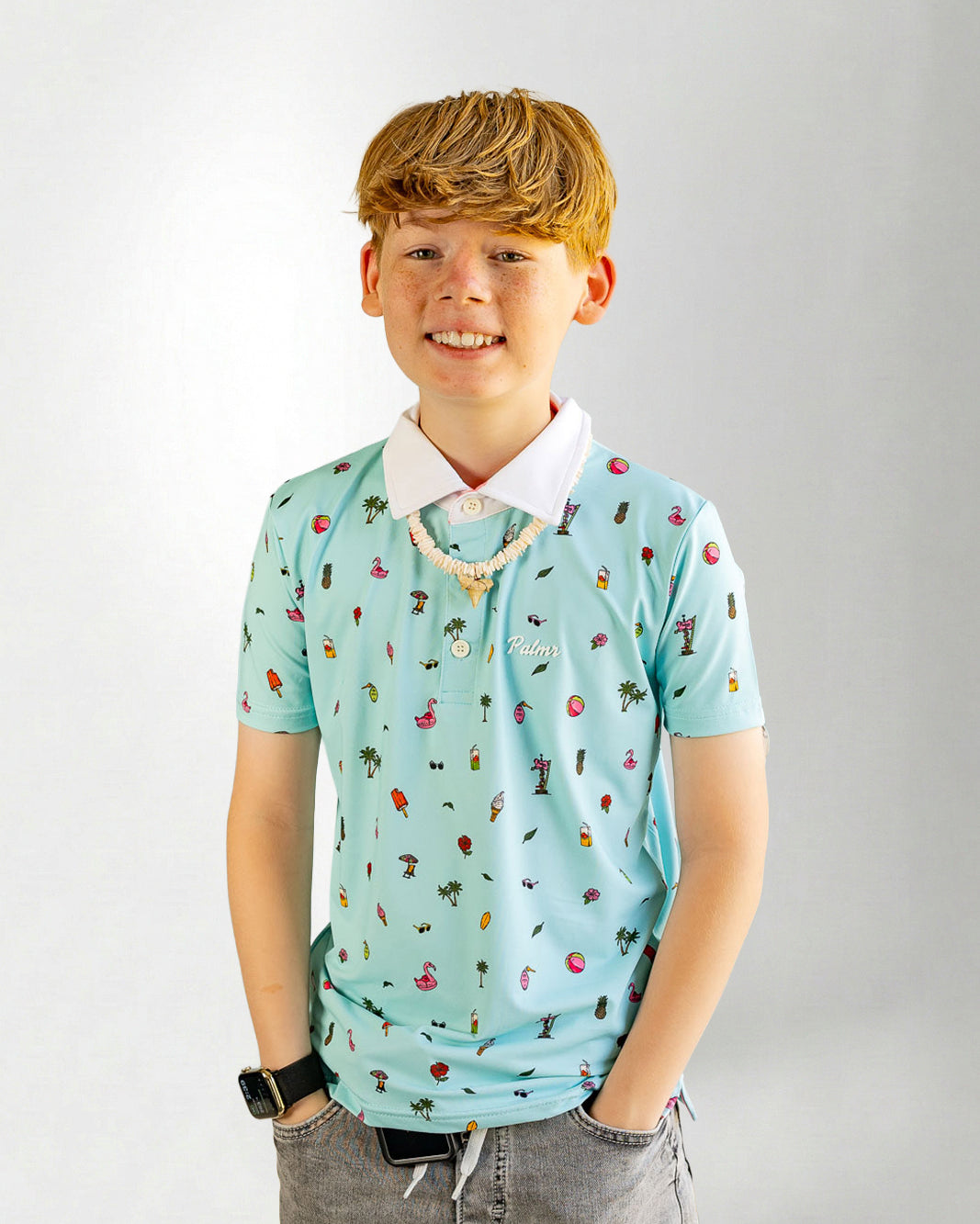 Young boy wearing a light blue polo shirt with colorful patterns on a plain background