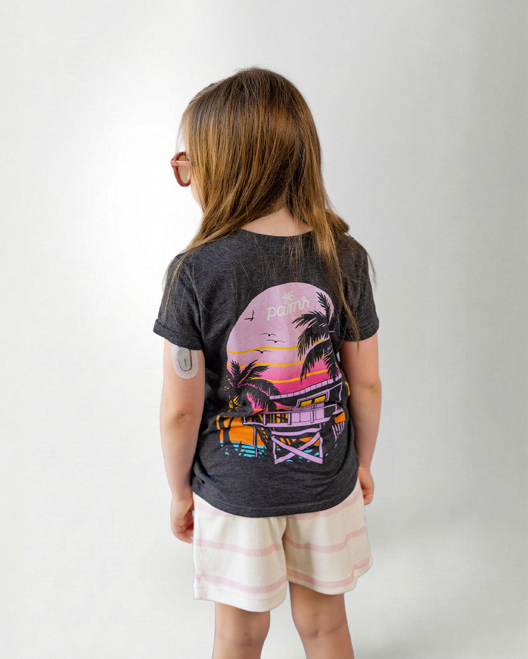 Child wearing a black t-shirt with a colorful graphic design on the back, standing against a plain background.