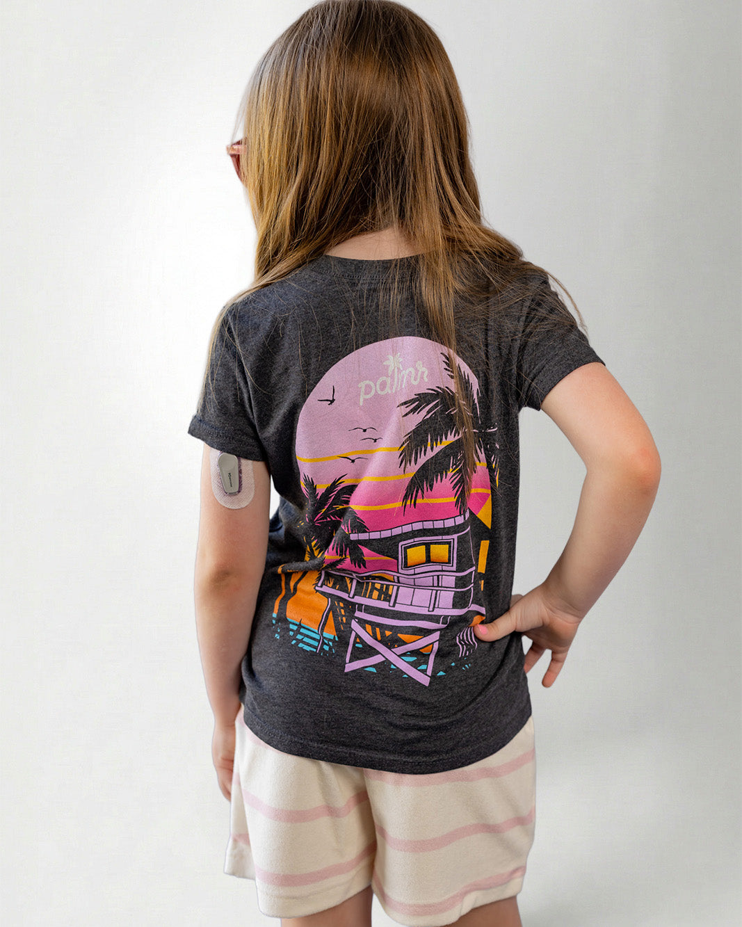 Child wearing a black t-shirt with a colorful graphic design on the back, standing against a plain background.