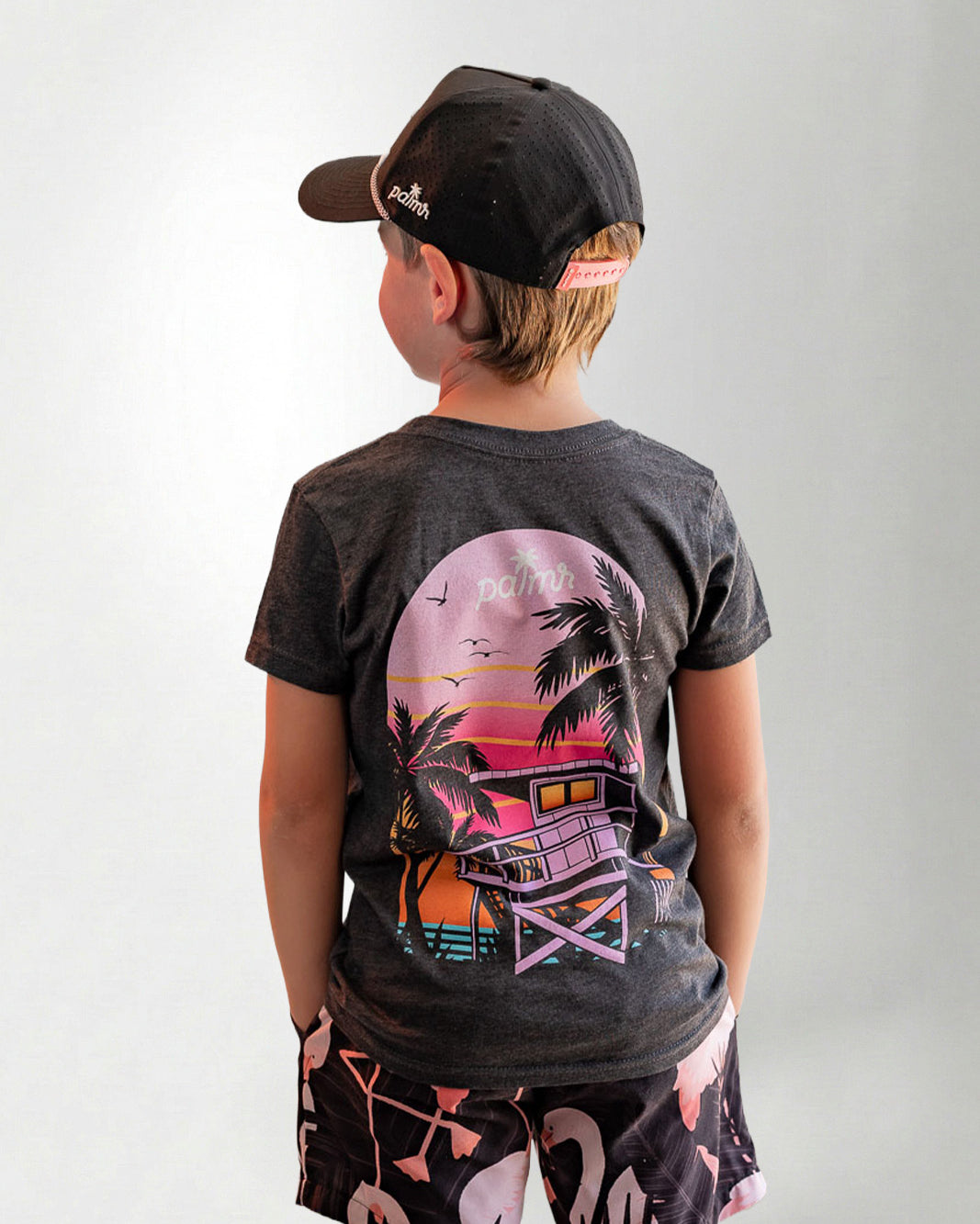 Child wearing a black t-shirt with a colorful graphic design on the back, standing against a plain background.