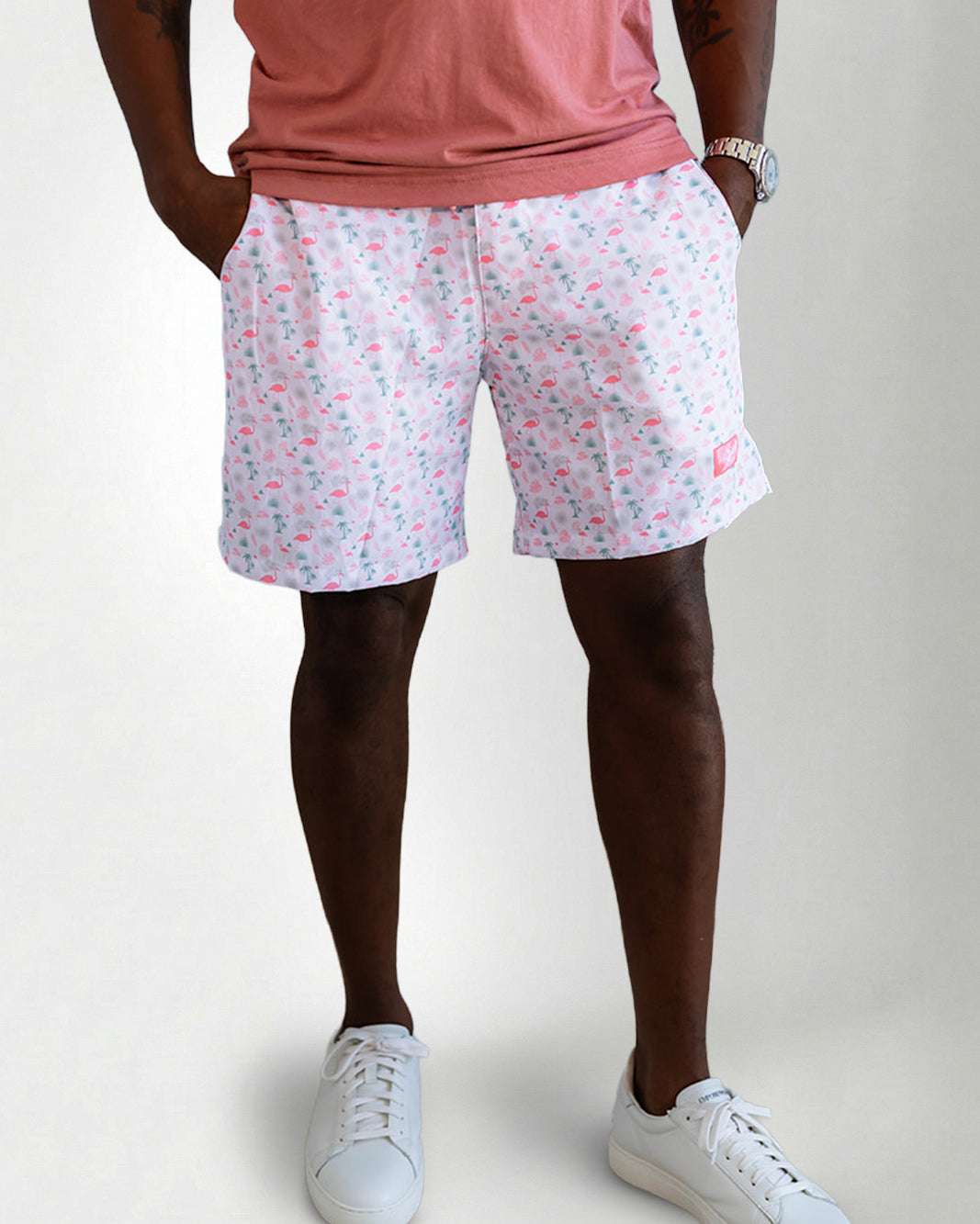 Person wearing pink floral shorts and white sneakers on a plain background