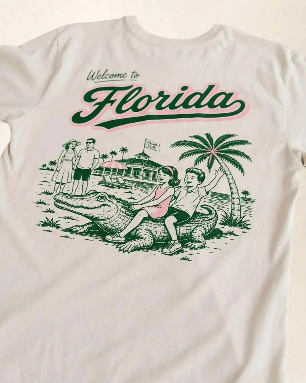 Welcome to Florida, Cream shirt showing a vintage style illustration of 2 kids riding a crocodile both smilind