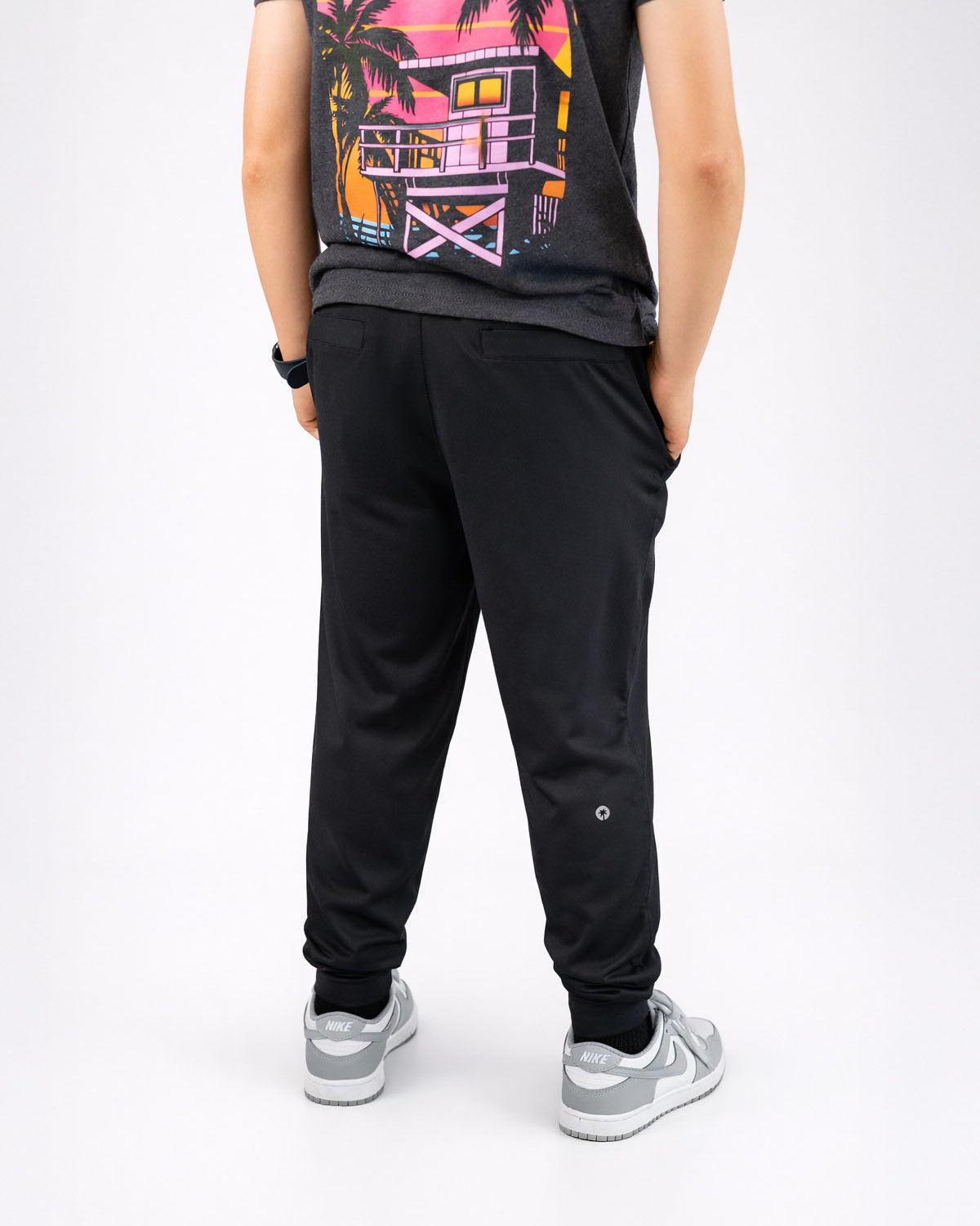 Person wearing black jogger pants and a graphic t-shirt on a white background