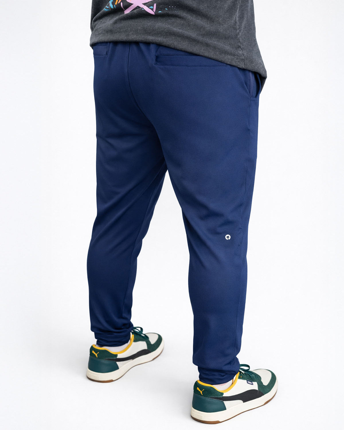 Person wearing navy blue jogger pants with a white background
