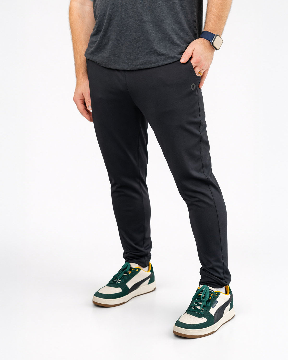 Person wearing black pants and green sneakers on a white background