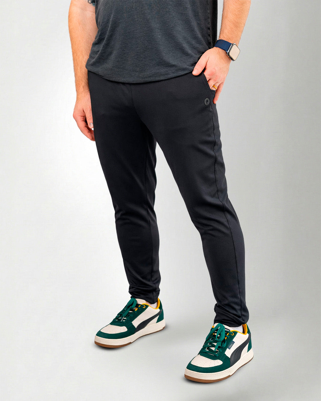 Person wearing black pants and green sneakers on a white background