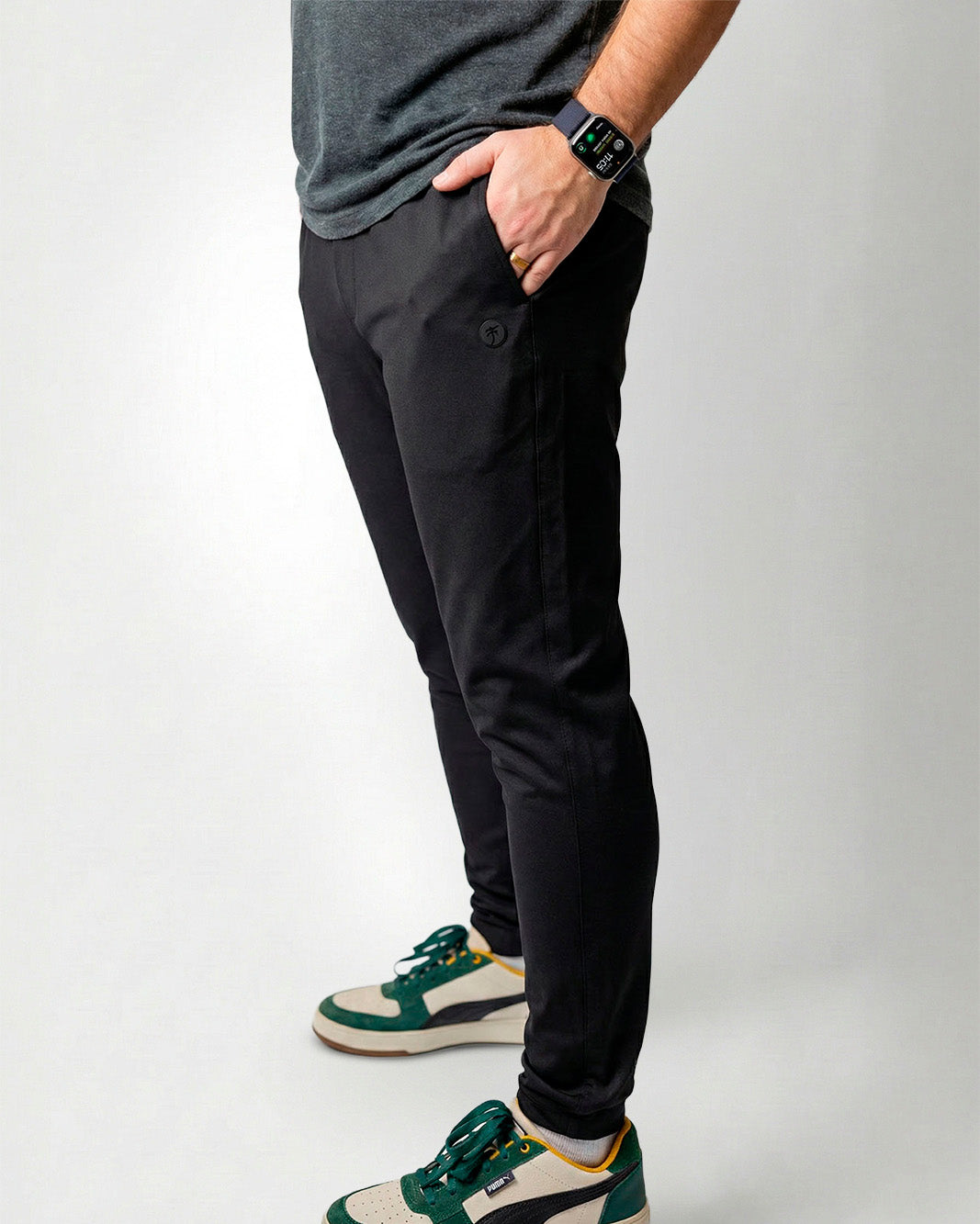 Person wearing black pants and green sneakers on a white background