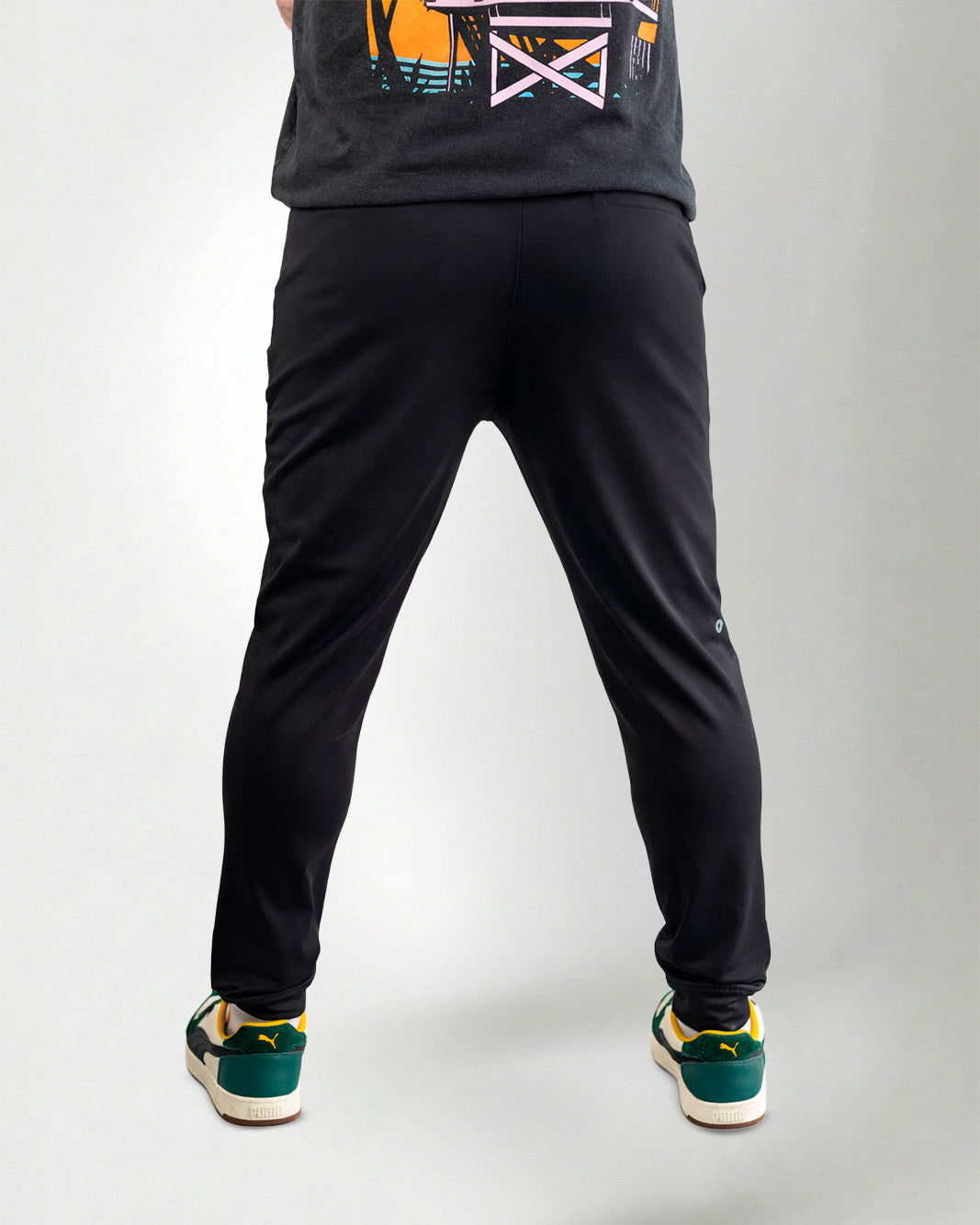 Person wearing black pants and green sneakers on a white background