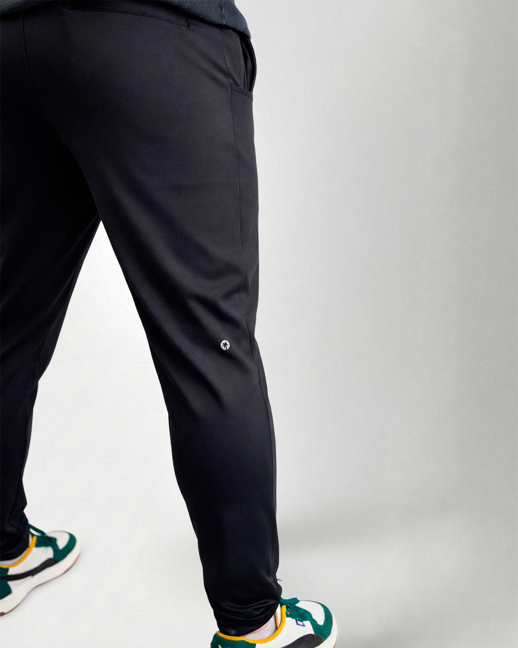 Person wearing black pants and green sneakers on a white background