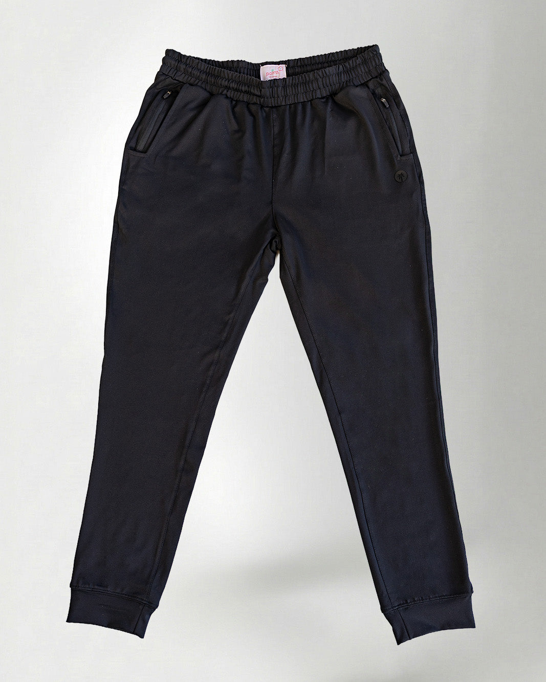 Person wearing black pants and green sneakers on a white background