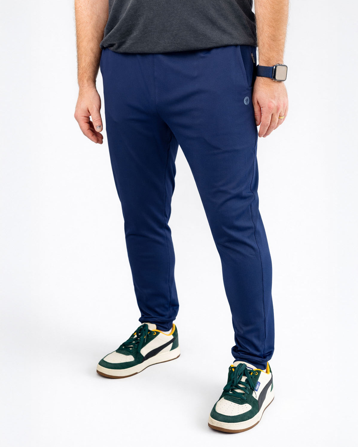 Person wearing blue pants and green sneakers on a white background