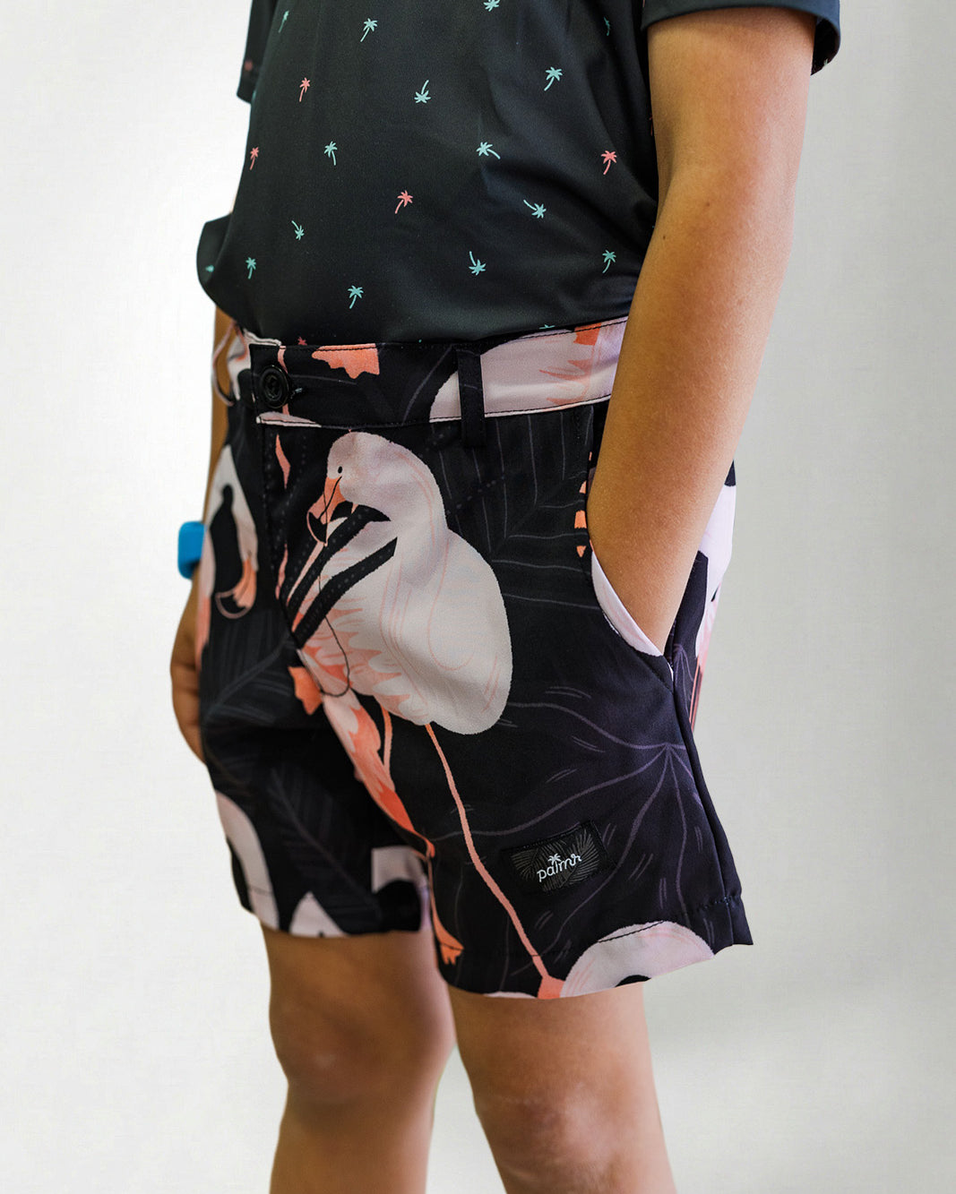 Person wearing a black patterned shirt and shorts with a white bird design on a plain background