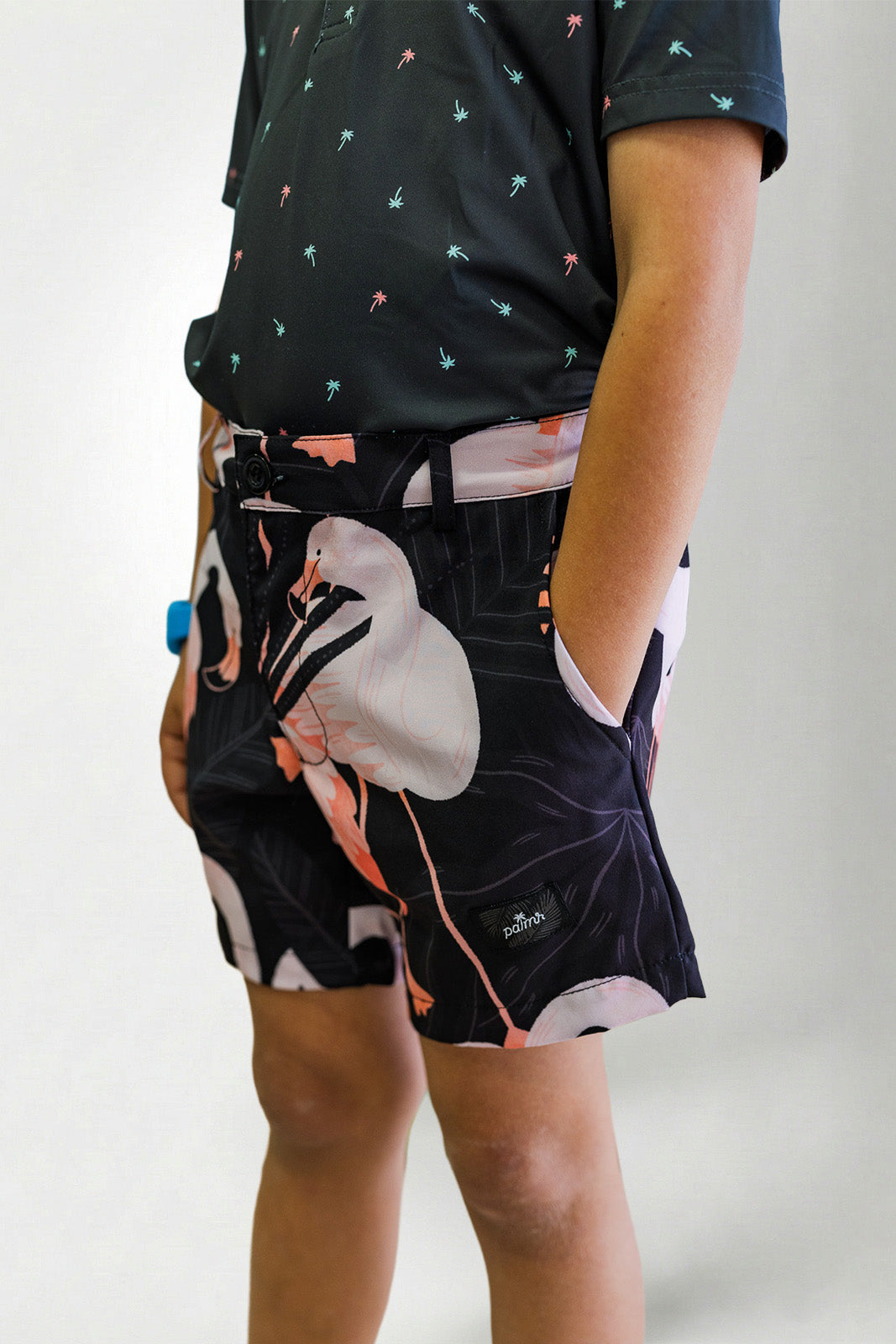 Person wearing a black patterned shirt and shorts with a white bird design on a plain background