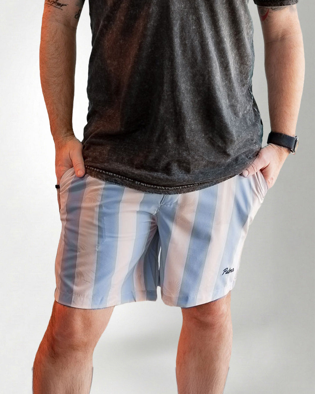 Person wearing a dark t-shirt and striped shorts on a plain background