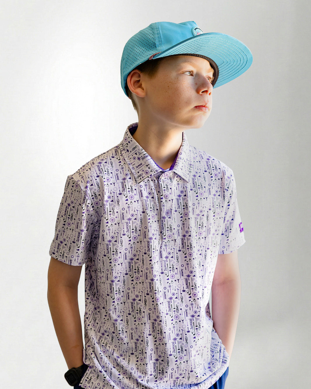 Child wearing a patterned shirt and blue cap against a plain background