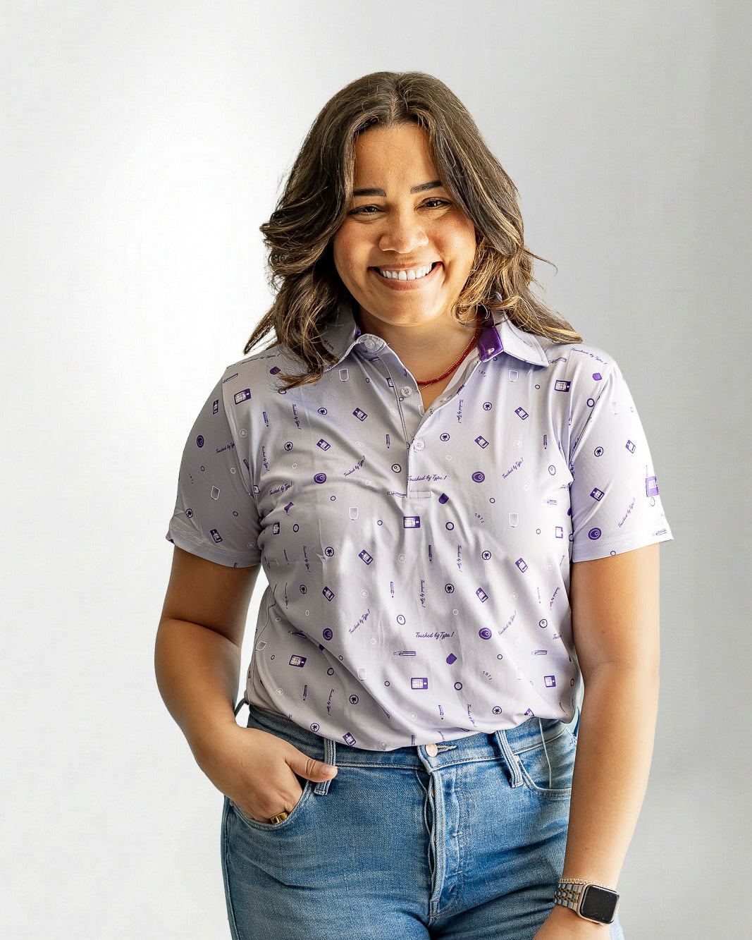 Woman wearing a patterned shirt and jeans against a plain background