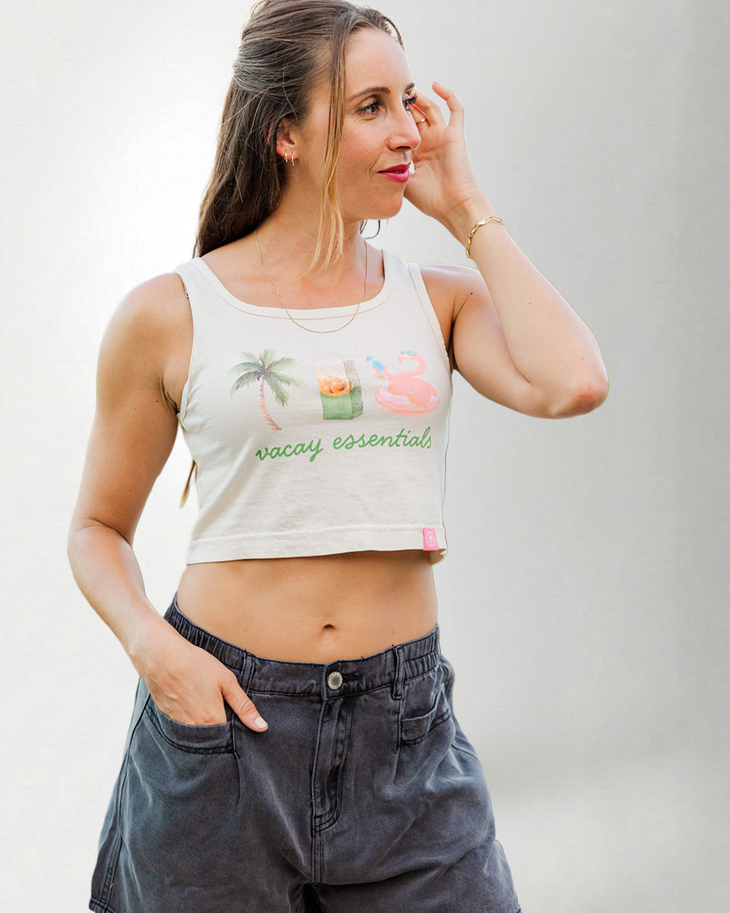 Woman wearing a tank top with a graphic design and text, standing against a plain background
