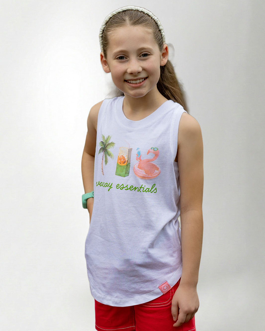 Young girl wearing a white sleeveless shirt with graphics and text, standing against a plain background