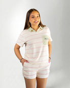 Person wearing a pastel striped outfit with a visible brand logo on a plain background