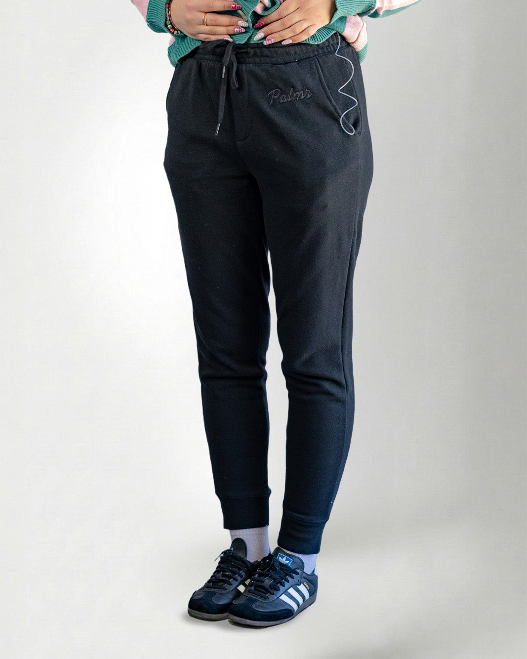 Person wearing black pants and black sneakers on a white background