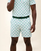 A man wearing a mint green and white checkered short-sleeve polo shirt and matching shorts with a dark green belt. The shorts feature a small embroidered 'Palmr' logo on the lower left leg.