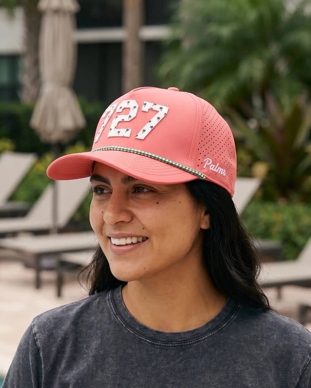 The 727 Signature Hat (Pink) worn on-model by the pool, three-quarter side view: white 727 on a pink crown, perforated panel, green rope.