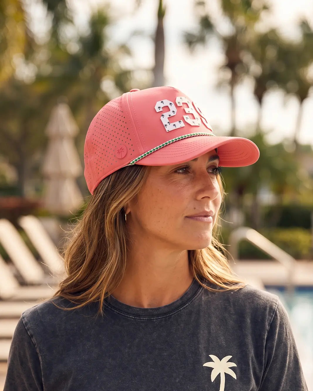 The 239 Signature Hat (Pink) worn on-model poolside, side view showing the perforated panel, green rope and white 239.