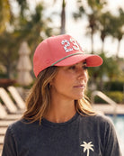 The 239 Signature Hat (Pink) worn on-model poolside, side view showing the perforated panel, green rope and white 239.