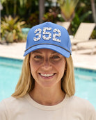 The 352 Signature Hat (Blue) worn on-model by the pool, straight-on close view: white raised 352 on a blue rope snapback.