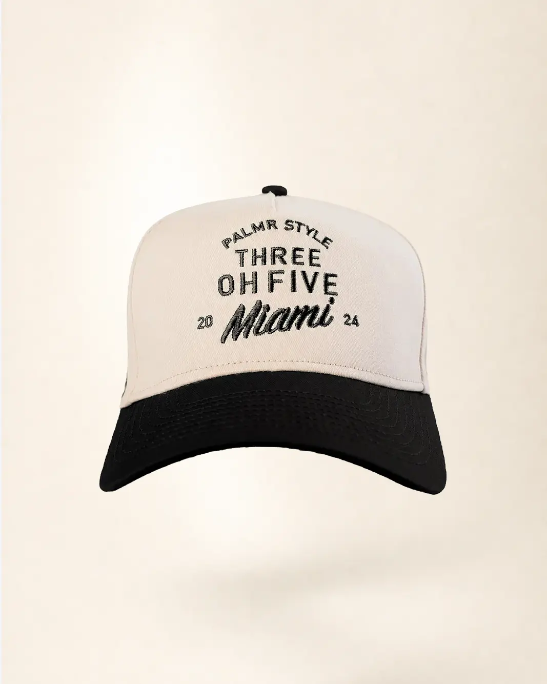 A baseball cap with a white front panel and black brim, featuring black embroidered text that reads 'PALM STYLE THREE OH FIVE Miami 2024' on a light beige background.