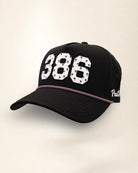 The 386 Signature Hat (Black), three-quarter view: white raised 386 with small palm print on a black rope snapback, pink and white rope, white Palmr script.