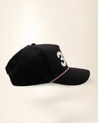 The 386 Signature Hat (Black), right side view: perforated side panel, palm badge, pink and white rope, edge of the white 386.