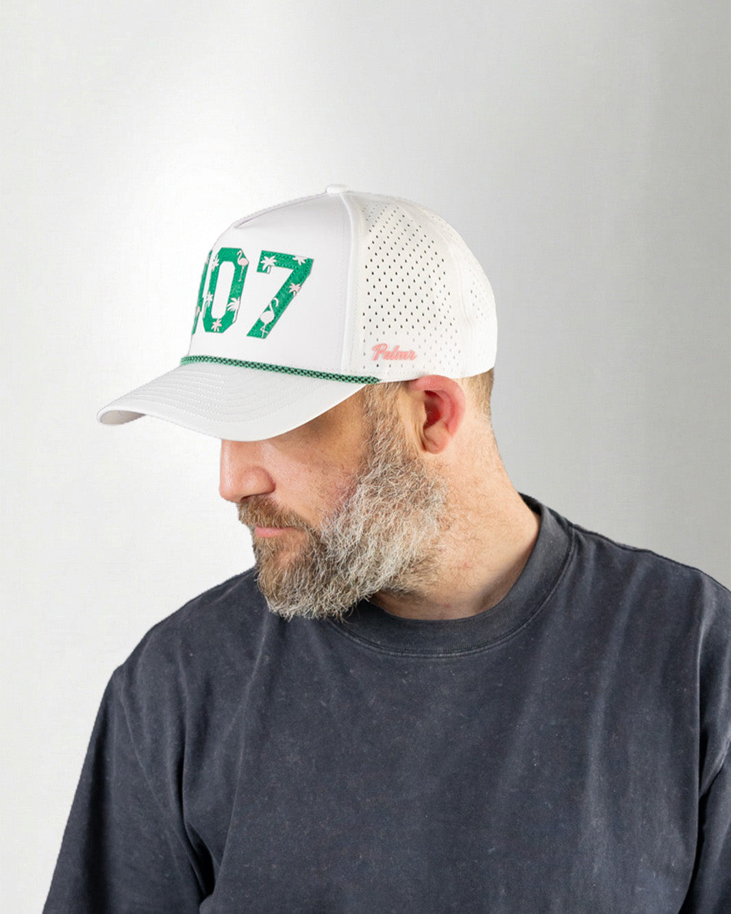 Man wearing a white cap with green text on a plain background