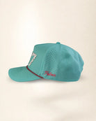 A turquoise blue perforated baseball cap with a curved brim, featuring a white and black patterned patch on the side and red embroidered script on the front panel.