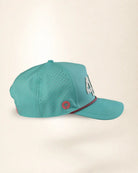 A turquoise blue baseball cap with perforated side panels, featuring a silver '4' on the side, a small red circular palm tree logo, and a red and black striped detail on the brim, set against a plain beige background.