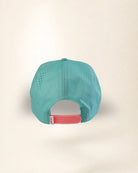A turquoise blue perforated mesh baseball cap viewed from the back, featuring a pink adjustable snapback strap with a white brand tag.