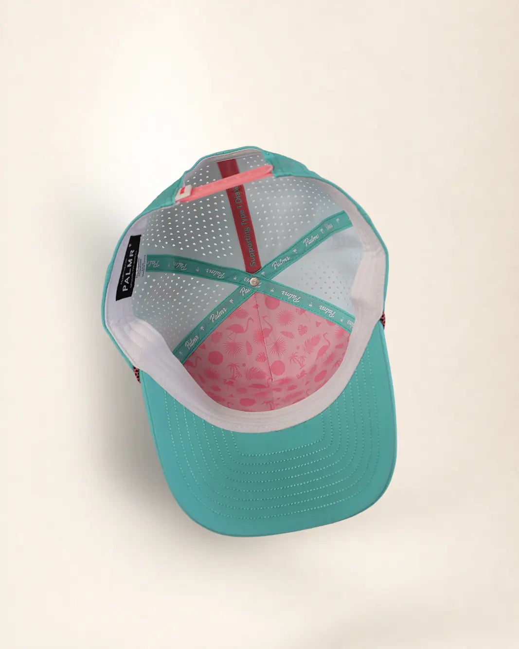 A turquoise and pink trucker-style cap shown from a top-down angle on a light beige background. The cap features a turquoise mesh front and brim, a white mesh back, a pink patterned front panel, and a pink adjustable strap.