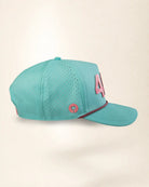 A turquoise mesh baseball cap with pink accents, including a large '4' on the side and a small circular palm tree logo patch, shown against a plain beige background.