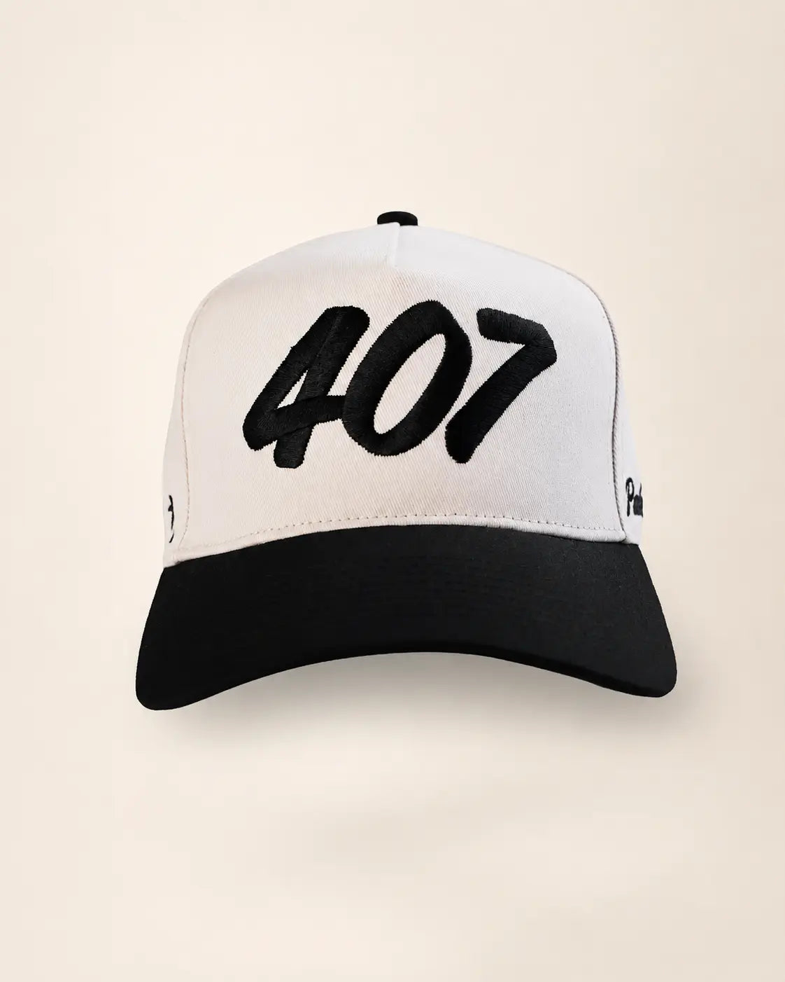 A black and white baseball cap featuring the number '407' embroidered in black across the white front panel, set against a solid light beige background.