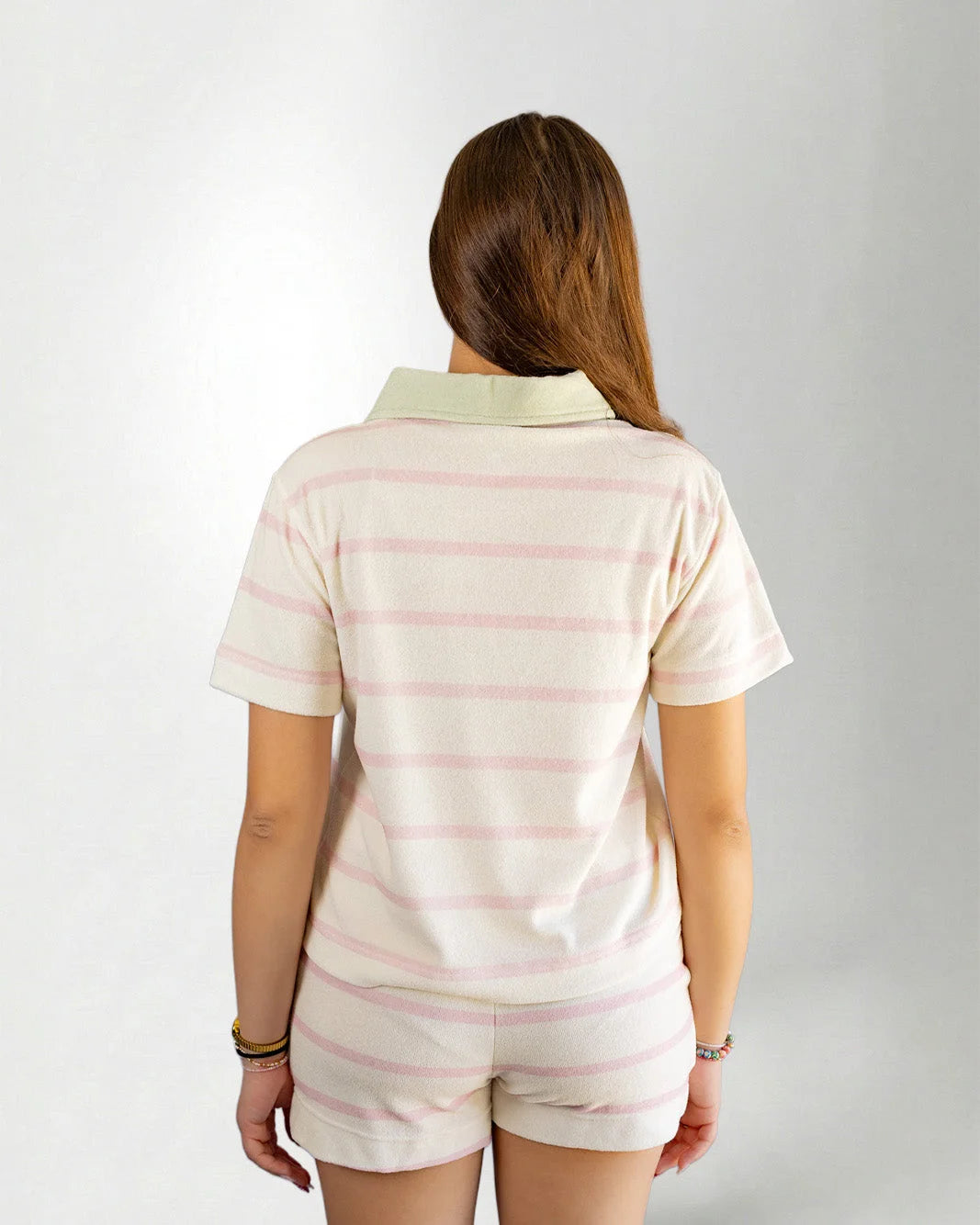 Person wearing a pastel striped outfit with a visible brand logo on a plain background
