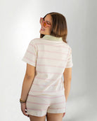 Person wearing a pastel striped outfit with a visible brand logo on a plain background