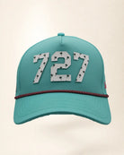 The 727 Signature Hat (Teal), front view: white raised 727 with small palm print on a teal crown, pink and black rope along the brim.