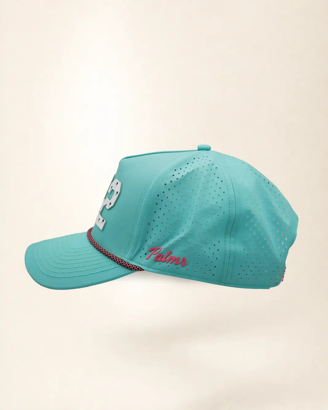 The 772 Signature Hat (Teal), left side view: pink Palmr script, perforated side panel, pink and black rope, edge of the white 772.