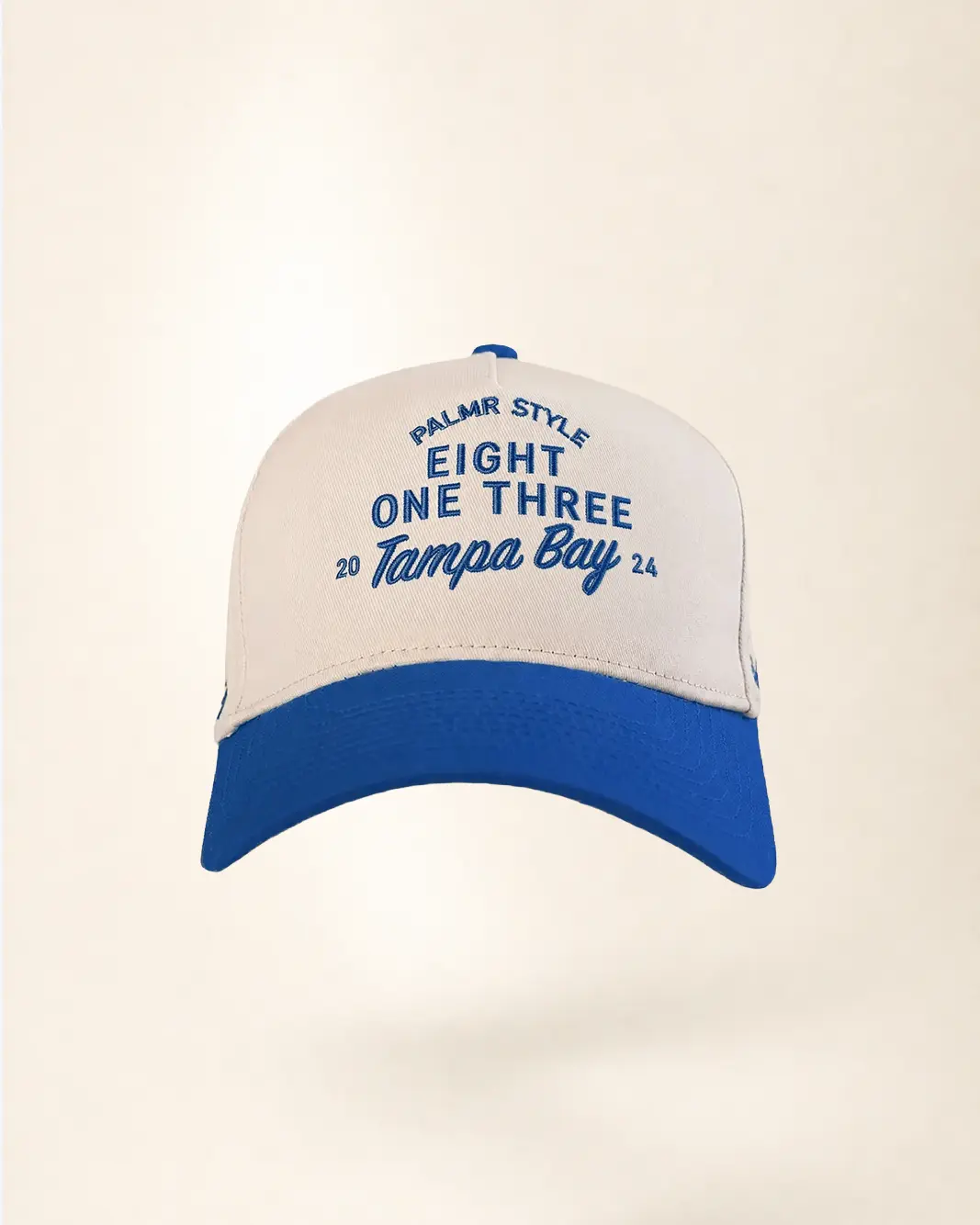 A baseball cap with an off-white crown and a royal blue brim, featuring blue embroidered text that reads 'PALMR STYLE EIGHT ONE THREE 20 Tampa Bay 24'.