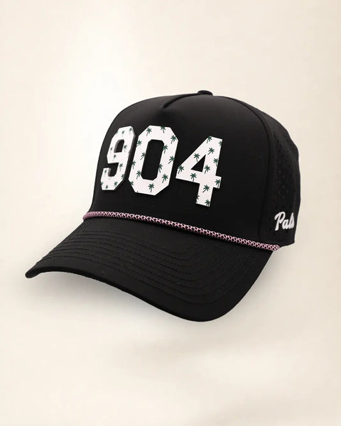 The 904 Signature Hat (Black), three-quarter view: white raised 904 with small palm print on a black rope snapback, pink and white rope, white Palmr script.