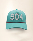 The 904 Signature Hat (Teal), front view: white raised 904 with small palm print on a teal crown, pink and black rope along the brim.