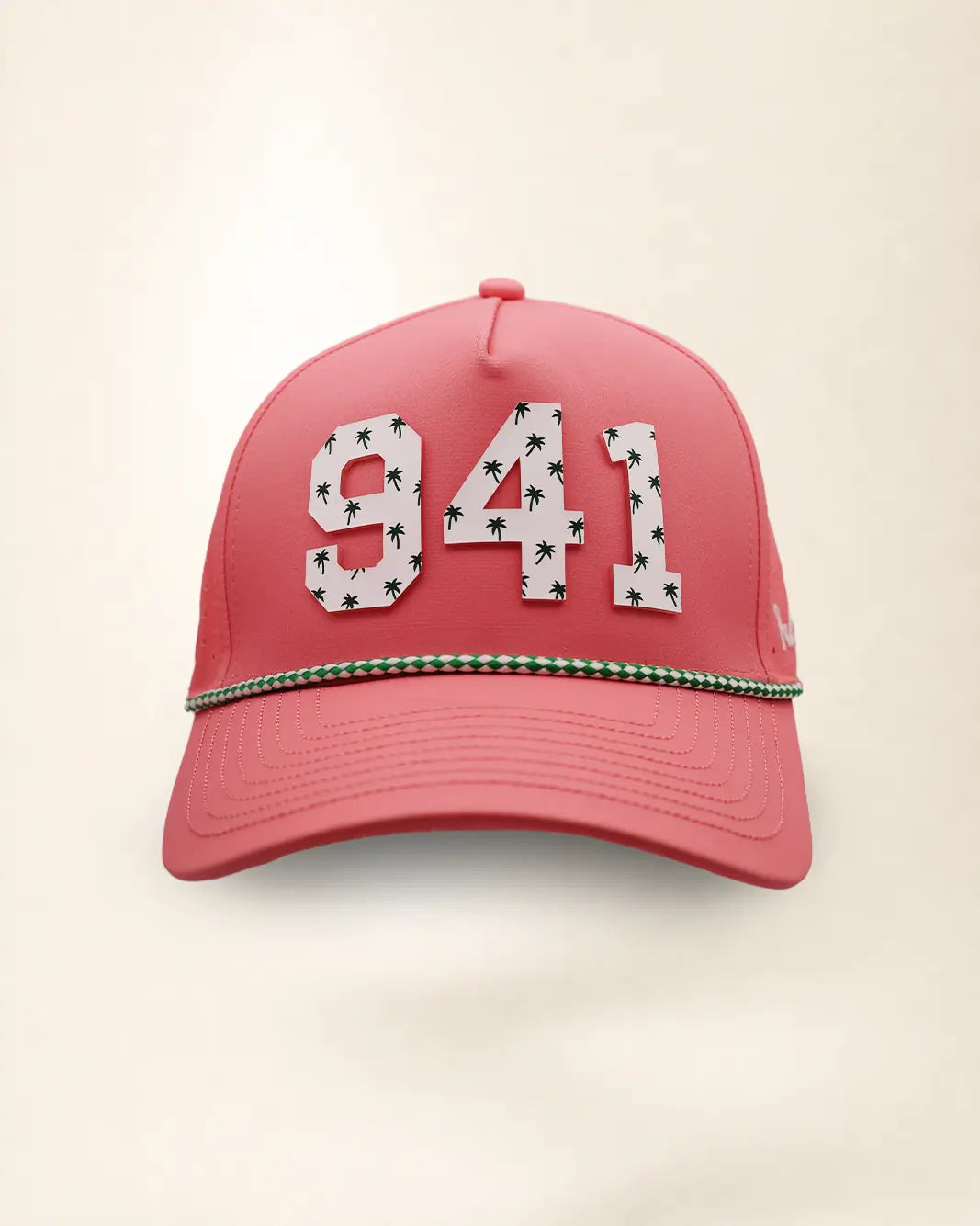A pink perforated baseball cap showcasing the '941' with a green and white patterned trim along the brim and white 'Palmr' script embroidery on the side, shown against a light beige background.